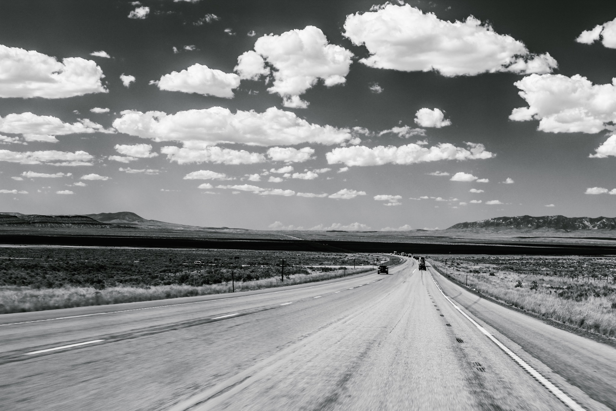 An open highway leading toward distant mountains beneath bright clouds