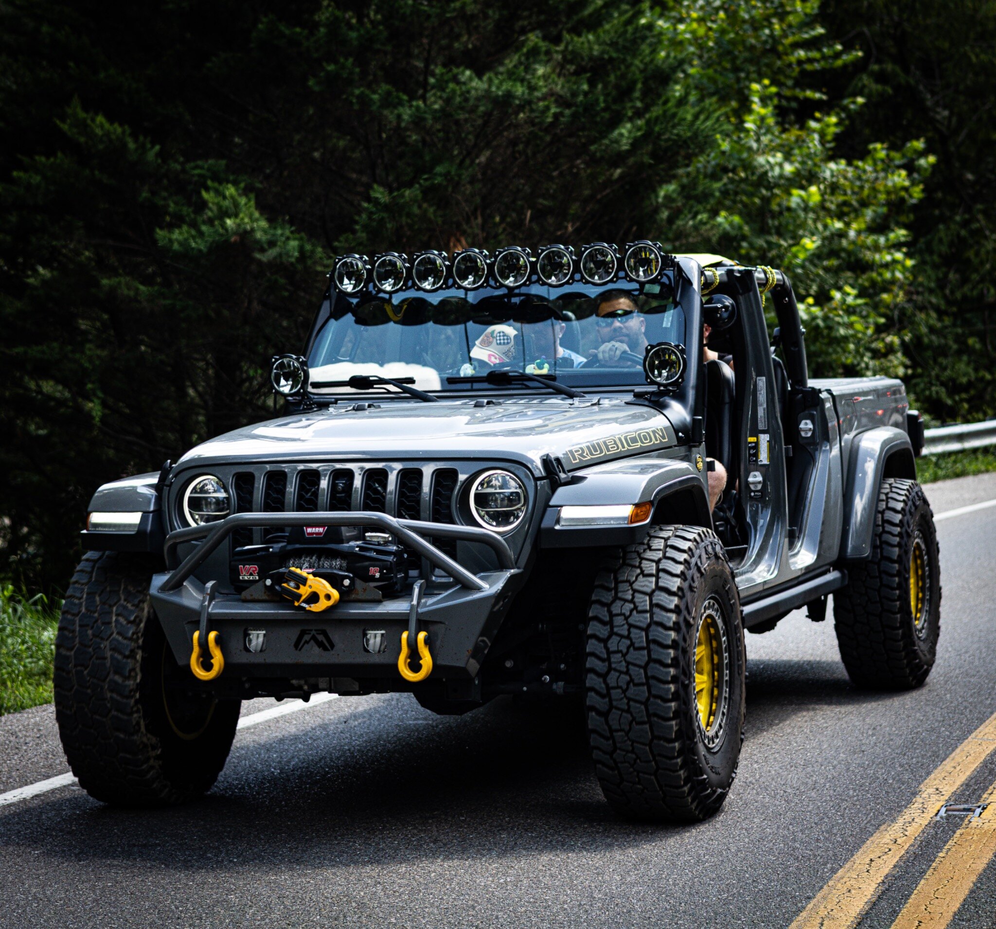 A doorless silver Jeep Wrangler Rubicon with yellow accents and a roof-mounted light array
